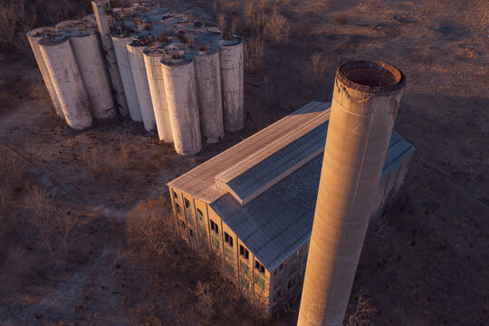 Aerial of Abandoned Factory in Big Field Catching Last Light at Sunset