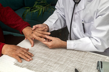 Doctor examining the hand of an elderly man with osteoarthritis