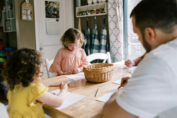 Little girls and their father coloring together at kitchen table