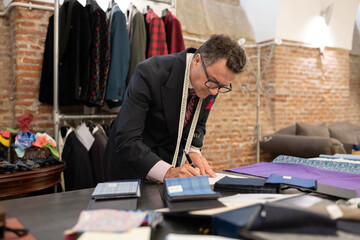 Elegant tailor drawing sketches in loft studio