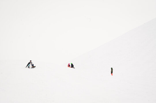 Wide Angle View of Father and Child Sledding Down a Steep Snowy Hill