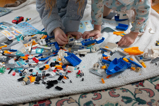 Siblings playing with toy bricks on the floor