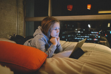 Tween on iPad in the evening. City Lights through the window