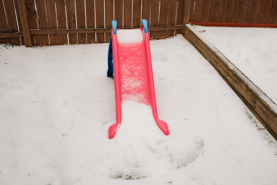 Toy slide covered with snow in back yard on winter day
