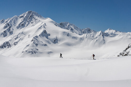 Side view of men with splitboards walking on snow covered mountain against clear sky