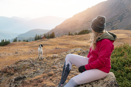 Woman camping with dog on mountain during vacation