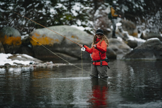 Woman fly fishing while standing in river during winter