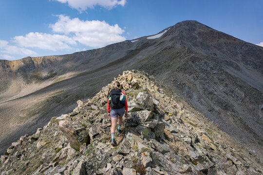 Rear view of female hiker walking on rocks at mountain