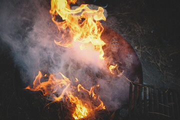 Smoke and Flames rise from a metal Campfire ring