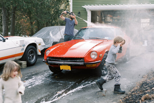 Little Kids Helping Their Father Wash A Classic Old Red Car Outside