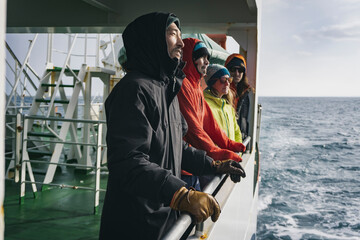 People in warm clothing looking at view while traveling in boat on river during vacation