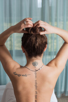 Young woman gathers her hair on top of her head and prepares for