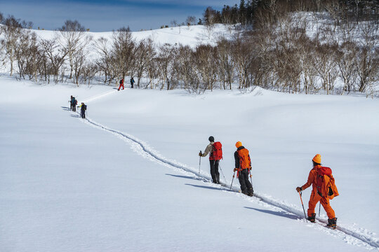 People with ski poles splitboarding on snowfield during vacation