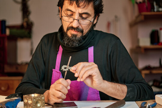 Jeweler craftsman working at work table inside workshop