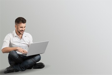 Portrait of young modern businessman holding laptop and looking at camera