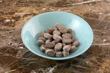 Salty licorice gummy candy pieces in blue snack bowl on table