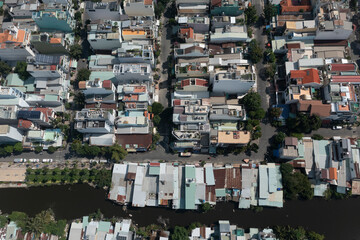 Top down aerial view of residential suburban area featuring rooftops and canal in Ho Chi Minh City, Vietnam on a sunny day.