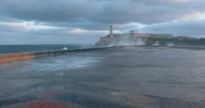 wave crashing on malecon with the Faro Castillo del Morro lighthouse 