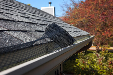 Roll of plastic mesh guard over gutter on a roof to keep it free of leaves, shallow focus on roll...