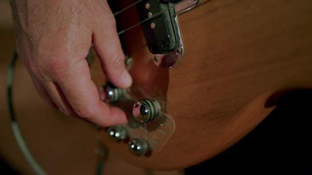 Bass guitar player adjusting knobs before show