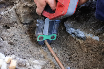 Plumber fixing an underground hot water pipe leaking with a tool