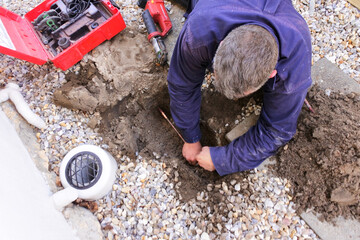 Plumber fixing an underground hot water pipe leaking with a tools