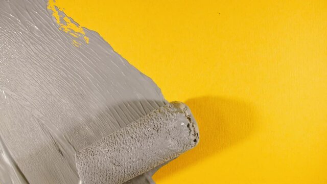 Abstract brushstrokes of gray paint brush, roller applied isolated on a yellow background. Gray paint smear texture. Textured artistic illustration. Smears of cosmetics. High quality 4k footage