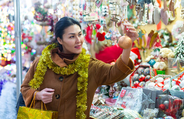 Asian woman purchasing decorations at christmas fair shop.