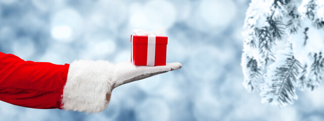 Santa Claus hand holding a wrapped Christmas present.