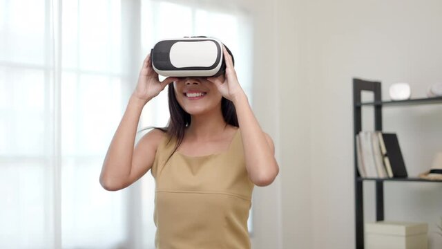 Young asian woman put on vr glasses into virtual simulated world metaverse. Future technology digital cyber universe. Person Enjoying an Experiences of Metaverse Virtual World.