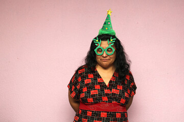 Fat Latina adult woman body positive Latina with Christmas hat and glasses shows her displeasure, sadness and anger at the arrival of December she hates Christmas
