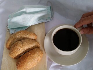 put mask off and hold cup of coffee to drink