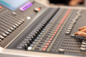 hand adjusting faders on an audio mixing console