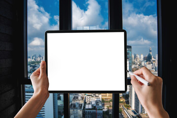 a woman using blank screen tablet with stylus on dark modern office desk with office supplies
