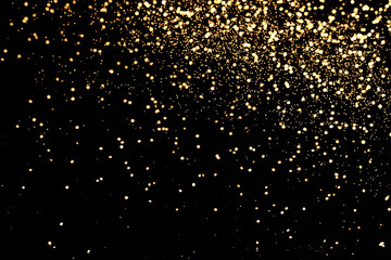 Black festive background. Abstract scattering of gold sparkles on black. Holiday backdrop,...