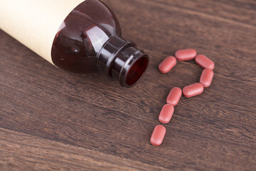 Question mark consisting of medicine bottles and pills