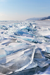 Baikal Lake in the January cold. Winter landscape with transparent ice blocks on a hummock ice field on a sunny frosty day. Ice travel and tourism. Natural seasonal background
