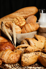 Close up of bread basket with milk, flour and ears of wheat on the table. Food and bakery concept. Vertical photo.