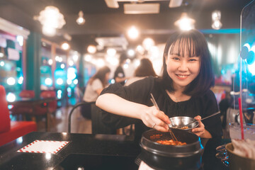 Portrait happy smile young adult asian woman eating ramyeon at Korean restaurant.