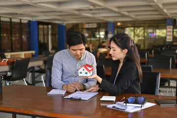 Young asian man signing agreement contract with real estate agent.