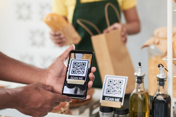 Hands of man scanning QR code with smartphone to get bonuses when buying food in cafe