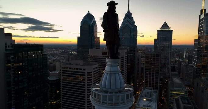 William Penn statue atop city hall in Philadelphia, PA, USA. Aerial at sunset, skyscapers line cityscape