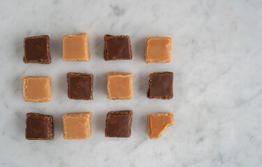 Assortment of Chocolate and Caramel Fudge on Marble Table from Above with Copy Space
