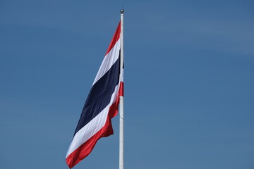 Naklejka premium Isolated Thai flag soars into blue sky