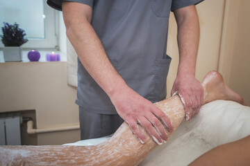 Obraz na płótnie Canvas Beauty treatments in the spa. Massage therapist applying scrub on the legs of the girl.