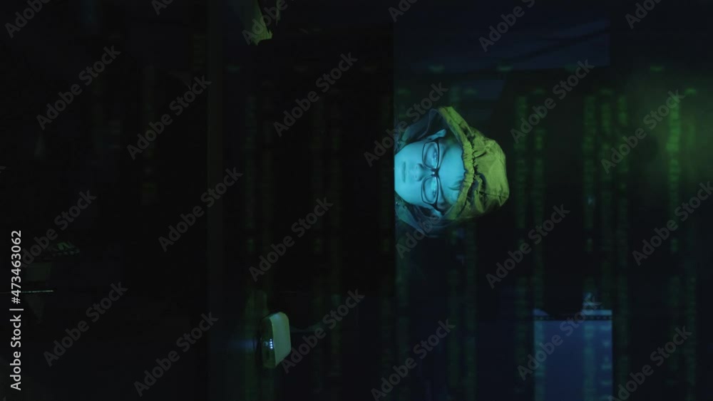 Poster vertical shot of a young male hacker in front of laptop with superimposed computer code moving up on