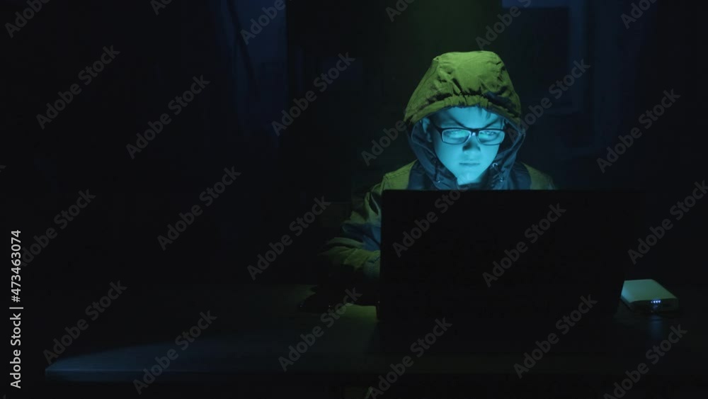 Poster young boy security hacker typing on a laptop computer at night. - static