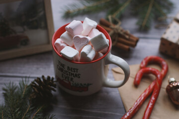 Cocoa with marshmallows, caramel candies, toys on a wooden photophone.