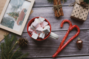 Cocoa with marshmallows, caramel candies, toys on a wooden photophone.