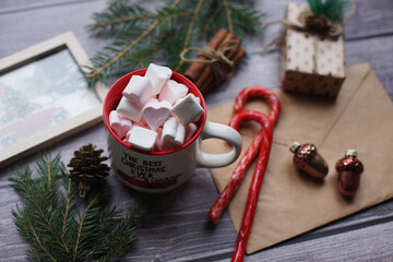 Cocoa with marshmallows, caramel candies, toys on a wooden photophone.
